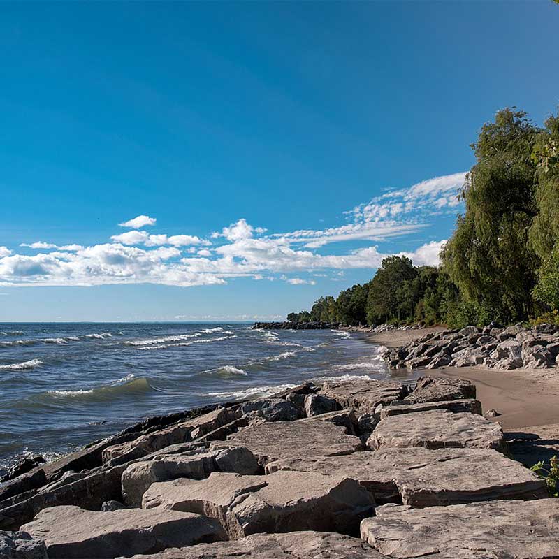 shore of lake ontario with rocky beach and blue skies