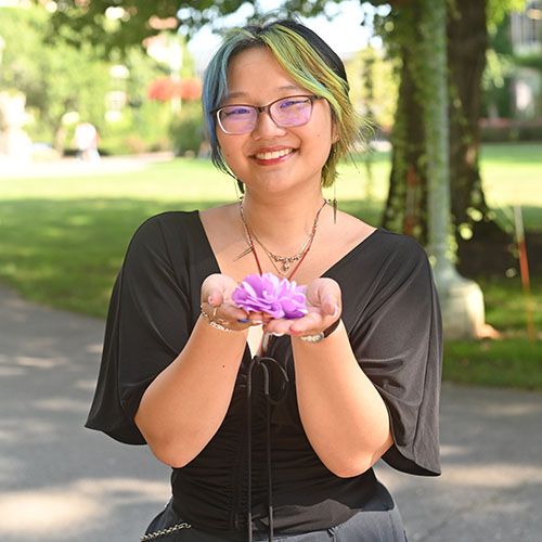 Catherine Lee ’25 holding a pink flower in her palms