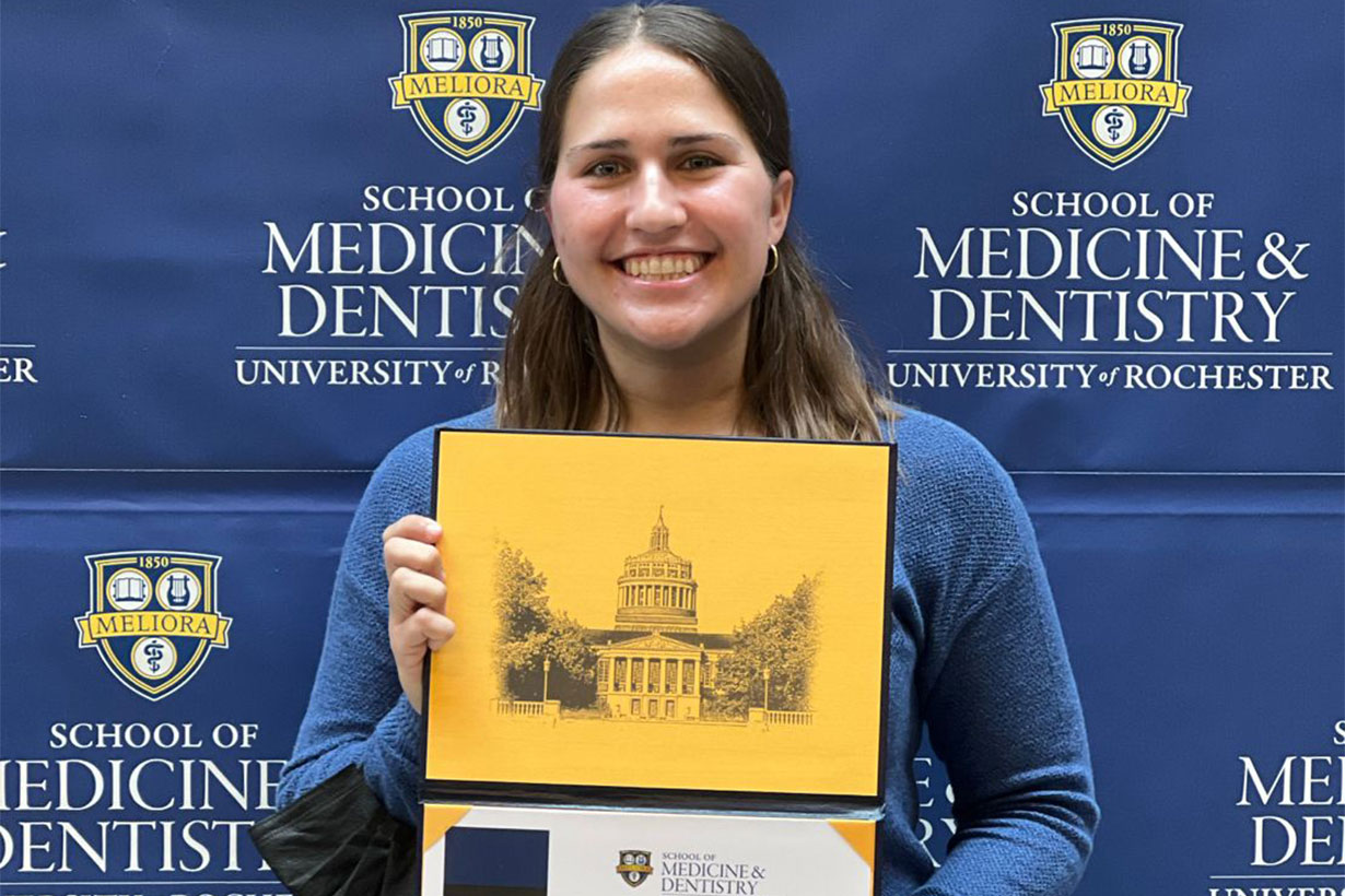 Knickole Bergman holding a fellowship aware in front of SMD backdrop