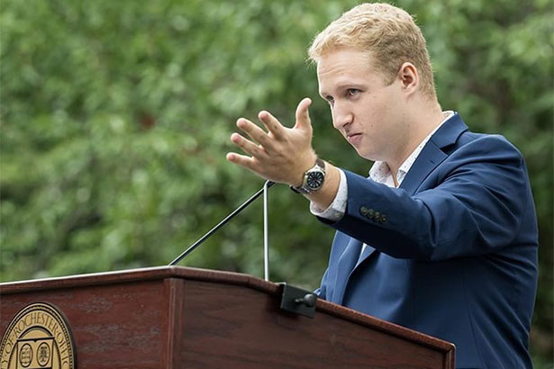 Elijah Bader-Gregory speaking in front of podium