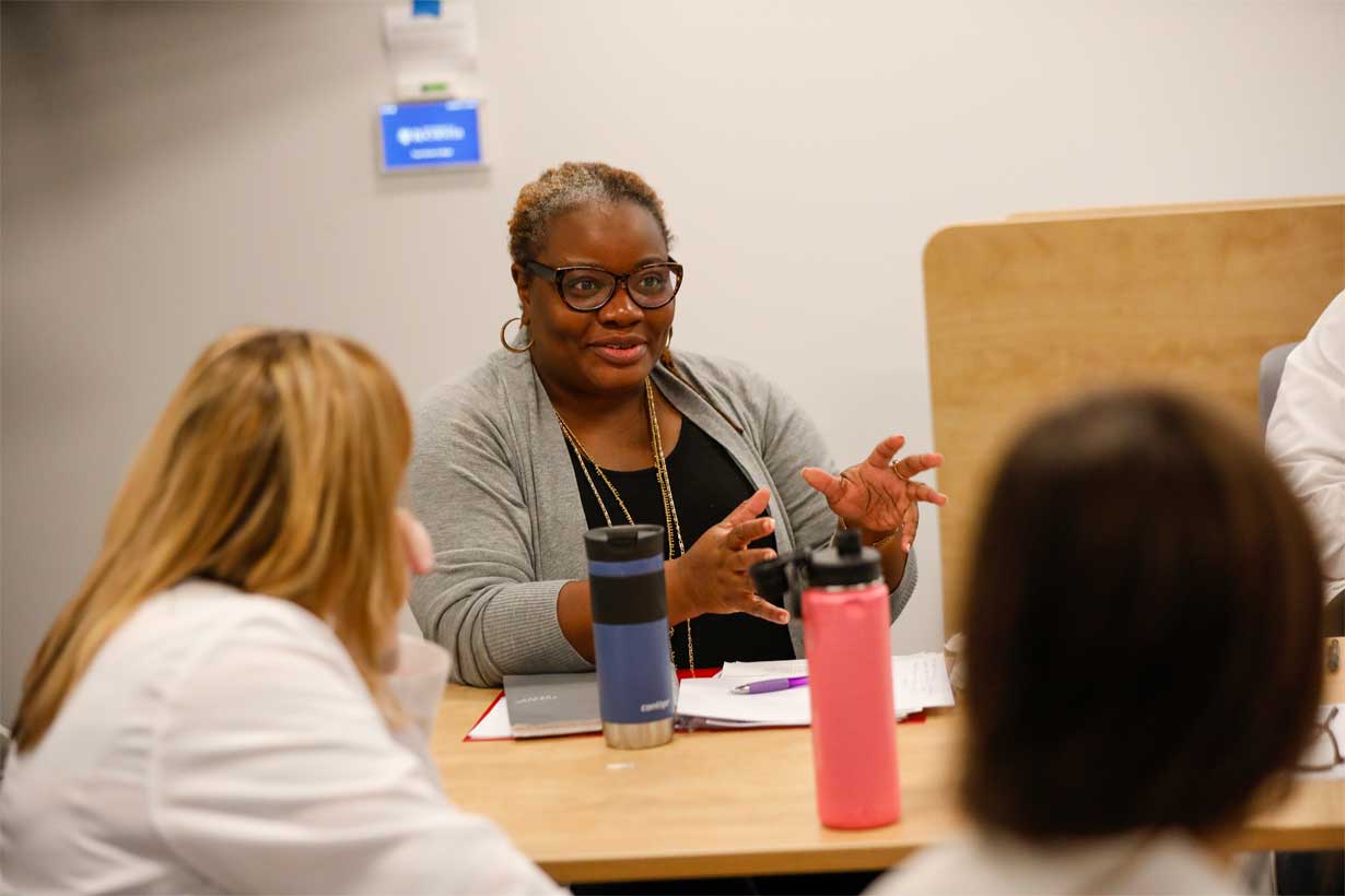 Natalie Leblanc sits at table talking to students