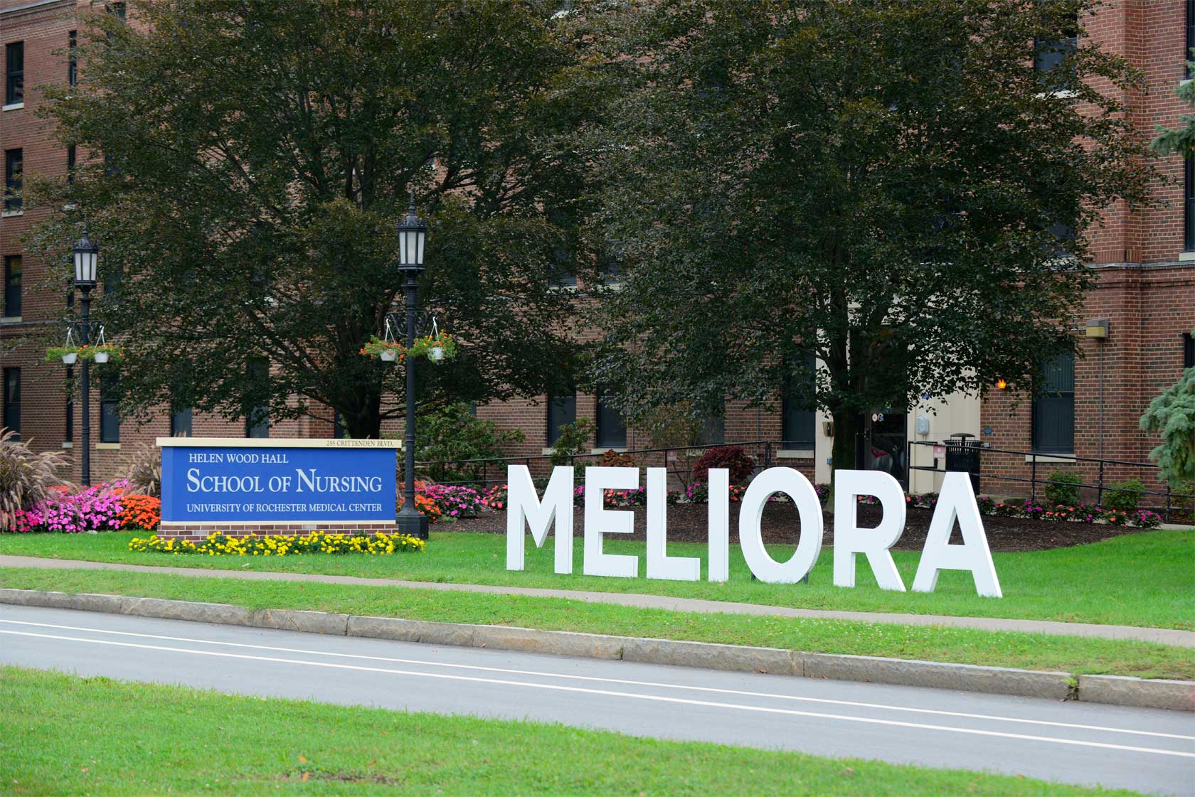 the School of Nursing, seen from the outside, a blue sign with the School of Nursing name, next to white letter signs spelling Meliora