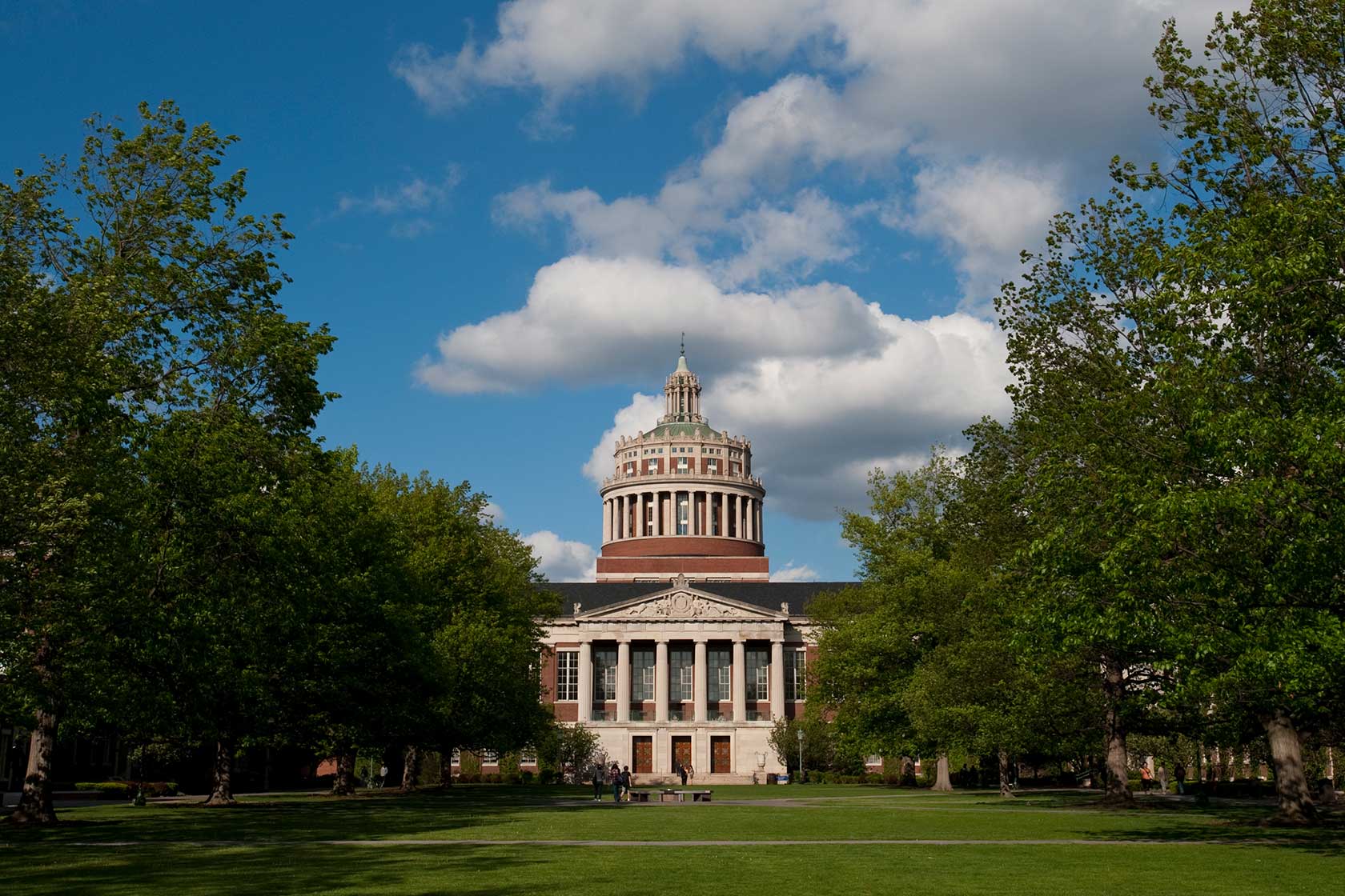 Rush Rhees library entrance, with green trees on either side in the quad