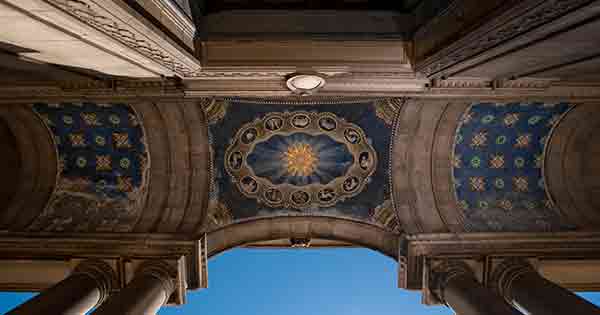 Upward view of a building ceiling that has columns, with a design pattern on a blue background