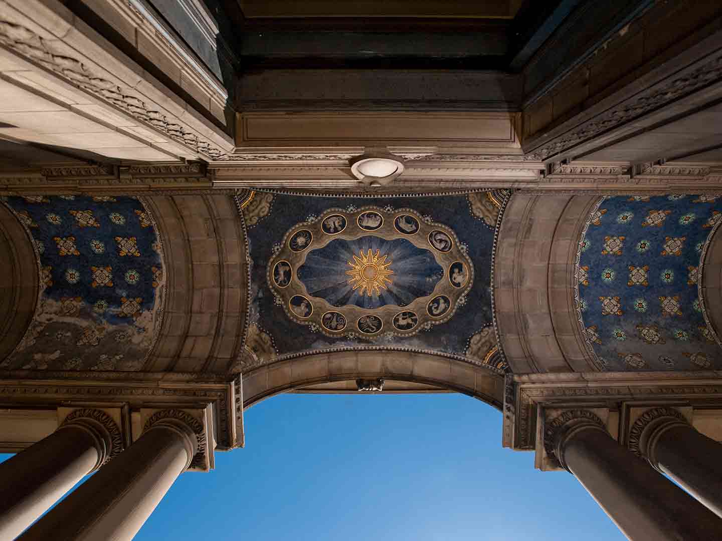 Upward view of a building ceiling that has columns, with a design pattern on a blue background