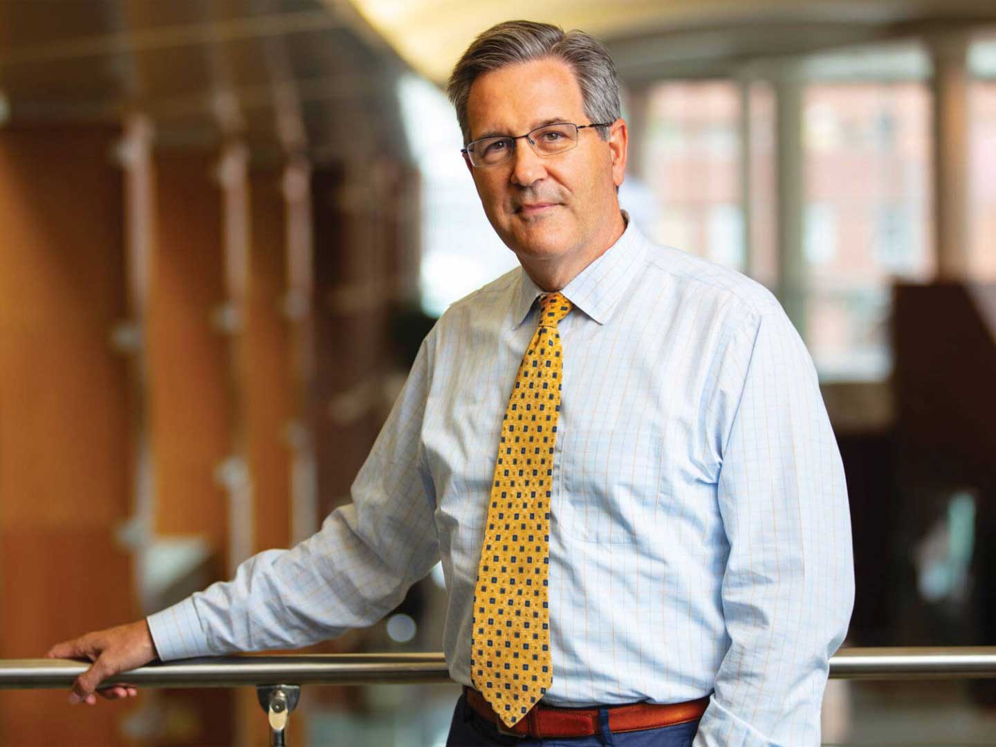 David Linehan, stands, smiling, leaning against a railing
