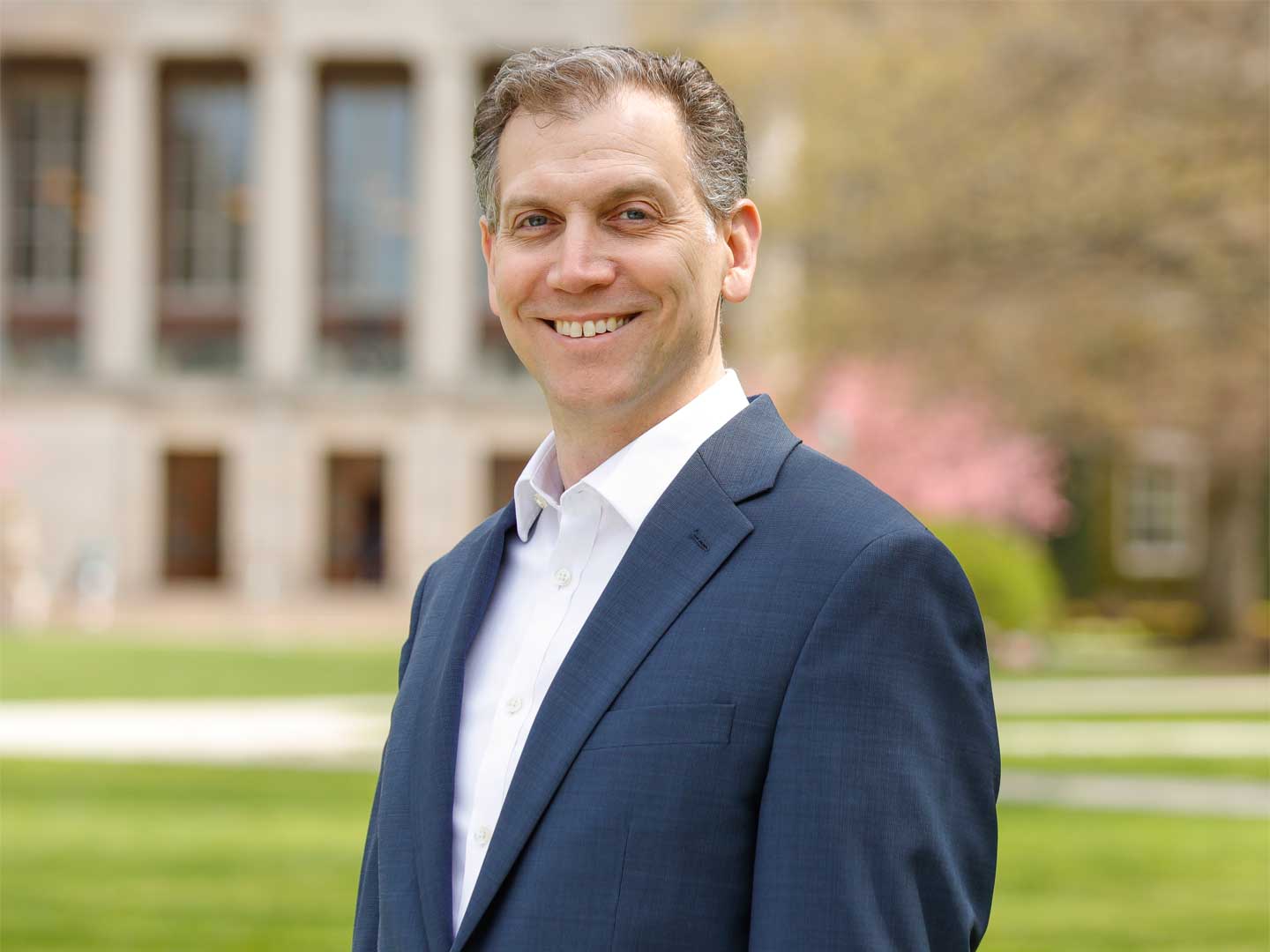 Mitch Lovett seen smiling, wearing blue blazer and white dress shirt