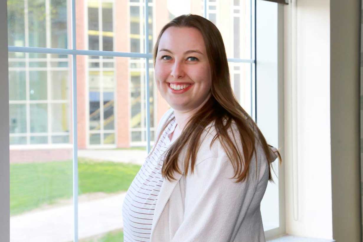 Amy Elbogen seen wearing white shirt, standing in front of a window