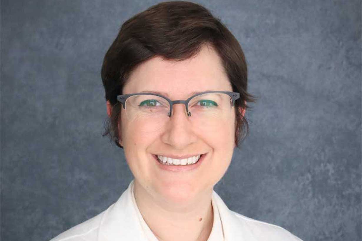 Laura DiChiacchio headshot, seen wearing glasses and a white lab coat
