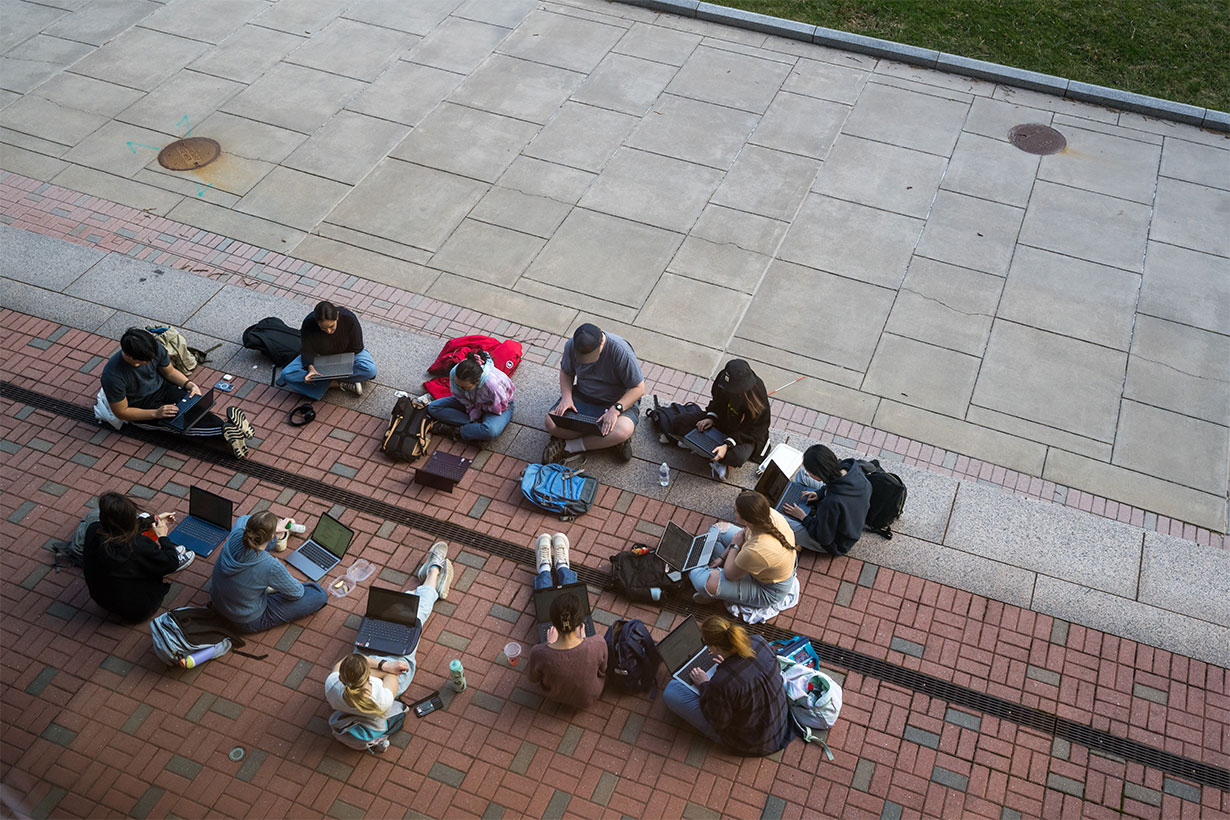 overhead image of students sitting around in a circle on laptops