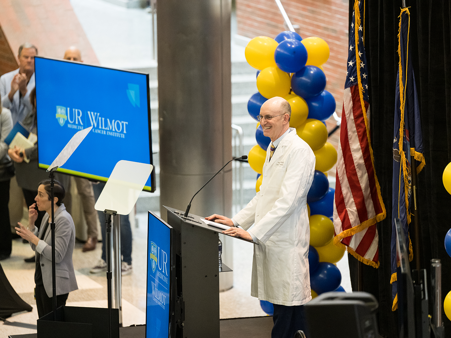 Dr. Jonathan W Friedberg in a white lab coat speaking at a lecturn