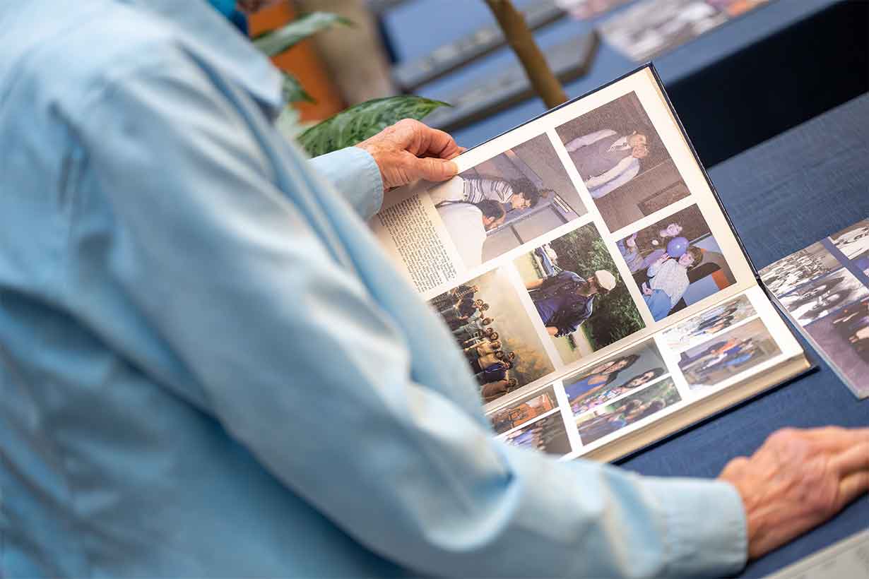 close up of a person with a long sleeve light blue shirt looking at a book with photos