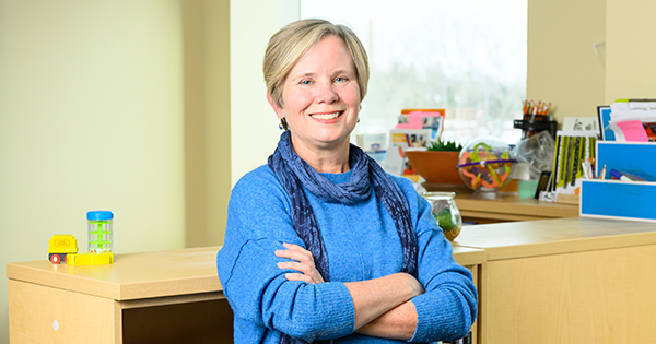 Lynn Cole, DNP ʼ98N (MS), ʼ21N posing with her arms folded, against a bookshelf