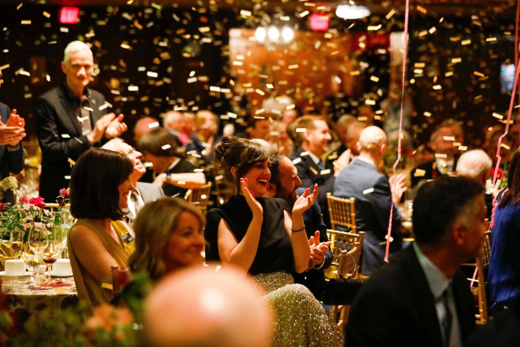 At MAG’s Flourish For All, Forever annual gala on May 9, 2026, attendees sitting in a banquet hall in formal attired applauding as confetti fall's down